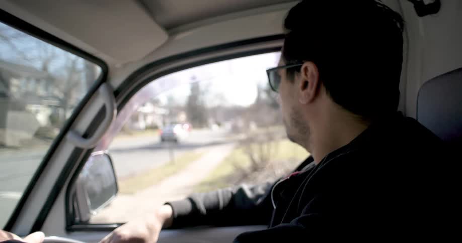 A man driving a vehicle on the quiet streets of a neighborhood