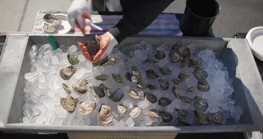 Close in the hands of a person with gloves preparing oysters