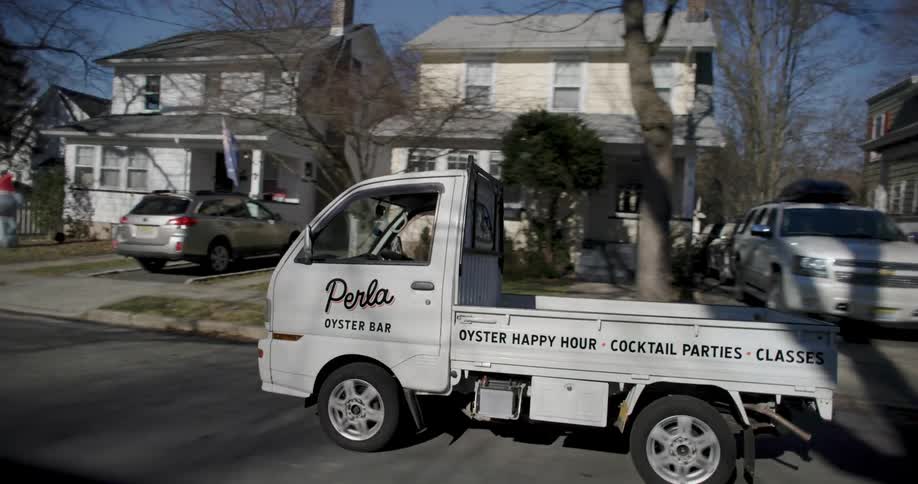 A man driving a truck on the street of a residential neighborhood