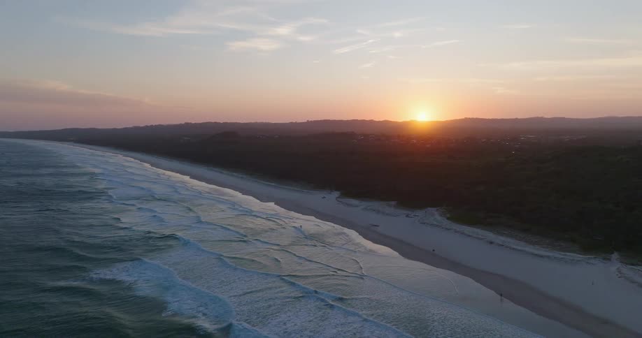 The sun is nearly below the horizon near an ocean beach