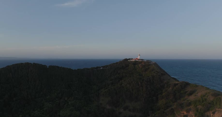 A remote lighthouse is located atop a mountain ridge near the ocean