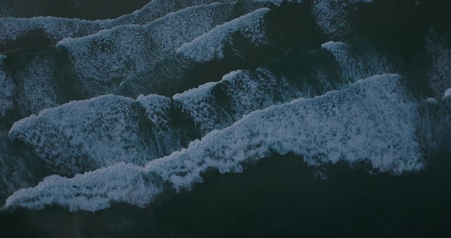 Aerial of ocean waves breaking against the beach