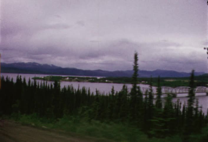 Moving view of a bridge spanning a large river on a cloudy day