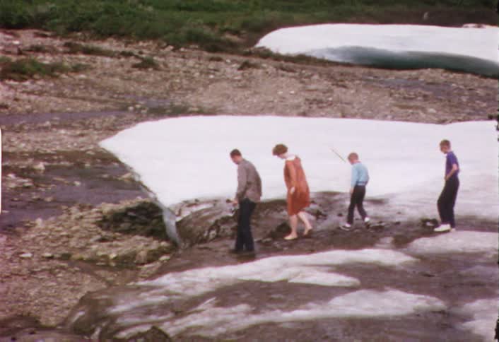 A family walks over a snowy and muddy field