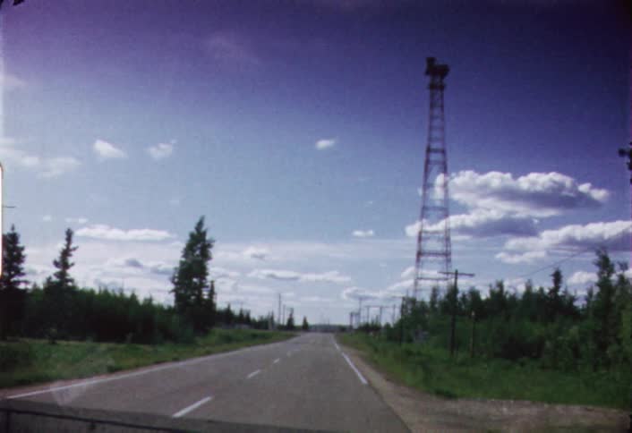 A watch tower stands tall above a tree lined road