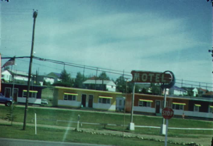 A vehicle drives by a motel during the day