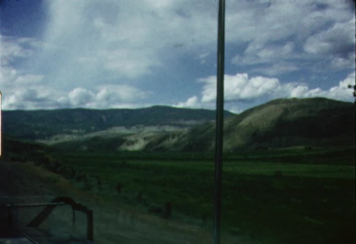 Mountain scenery passes by outside the window of a moving vehicle
