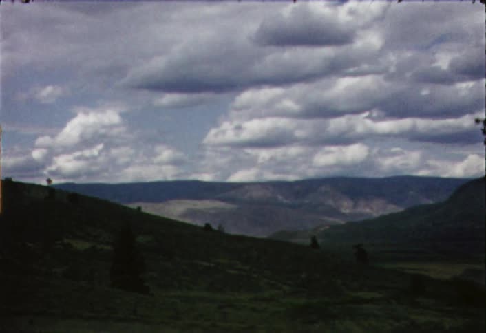 Moving and zooming view of some mountains on a cloudy day as seen through a window