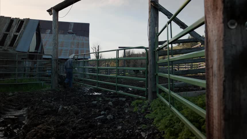 A man walking through a fence on a ranch