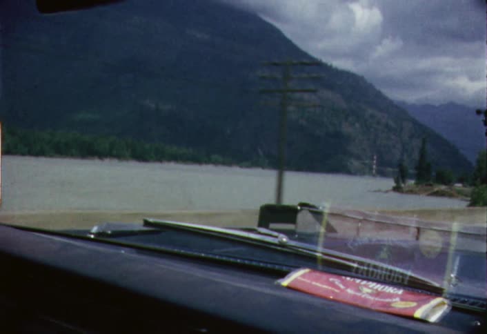 Passing view of a lake and mountain as seen from a moving car