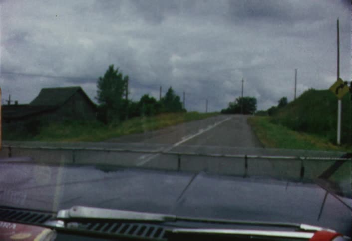 A car drives down a road lined with trees