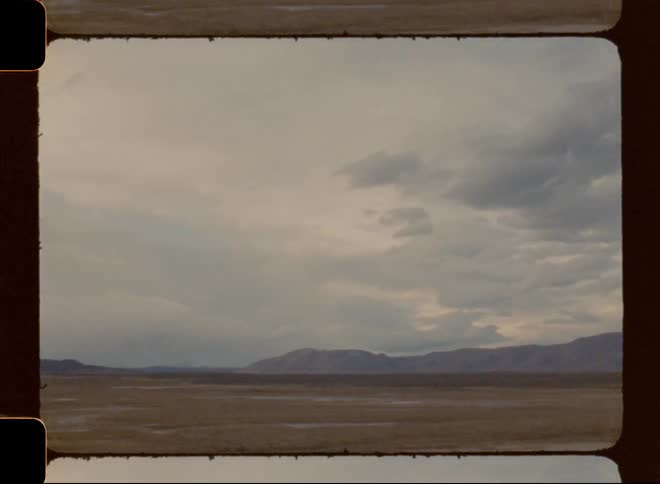 A desolate area of dead grass has dark storm clouds in the sky