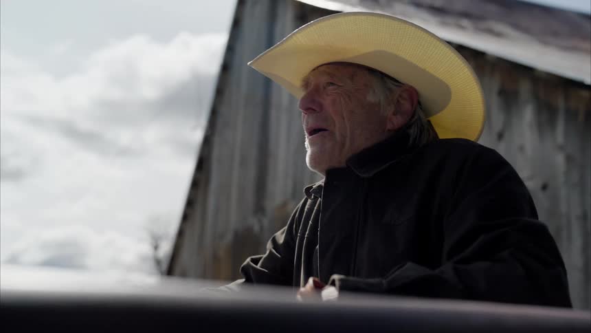 Portrait of an elderly man wearing a cowboy hat in an outdoor environment