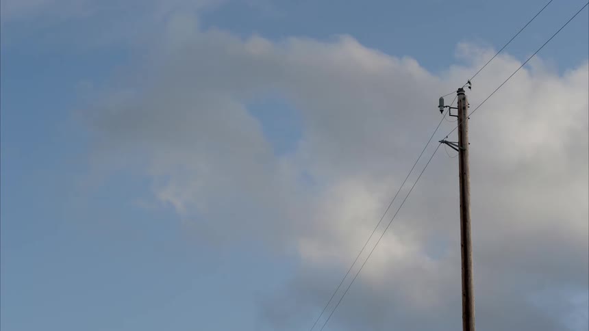 Some clouds moving slowly over some power lines