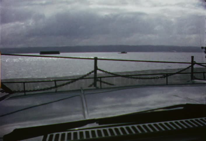 A car is sitting on a ferry as it crosses a body of water