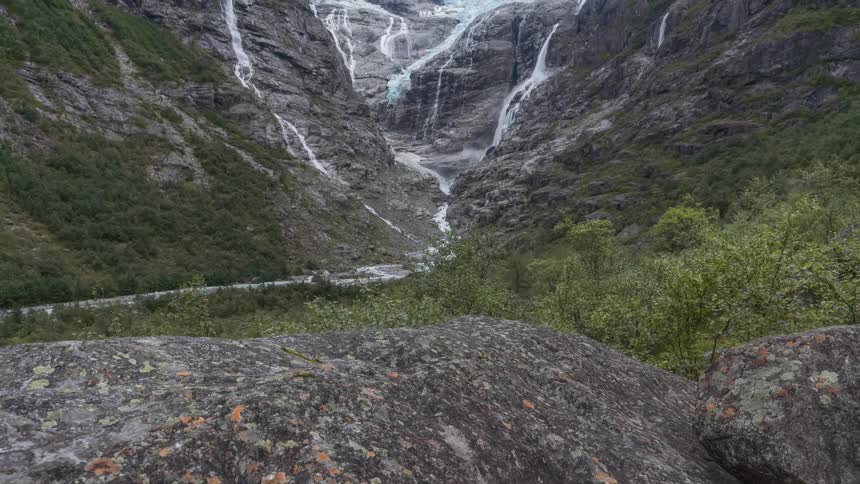 Water flows down the side of a mountain into a canyon on a windy day