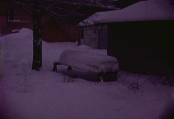 Small boat being stored outside a building in the snow