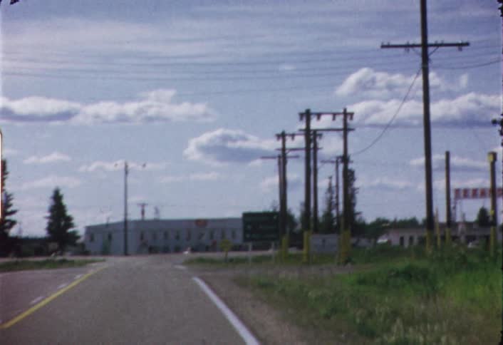 Moving view of a vehicle driving  down a two lane road as seen through its windshield