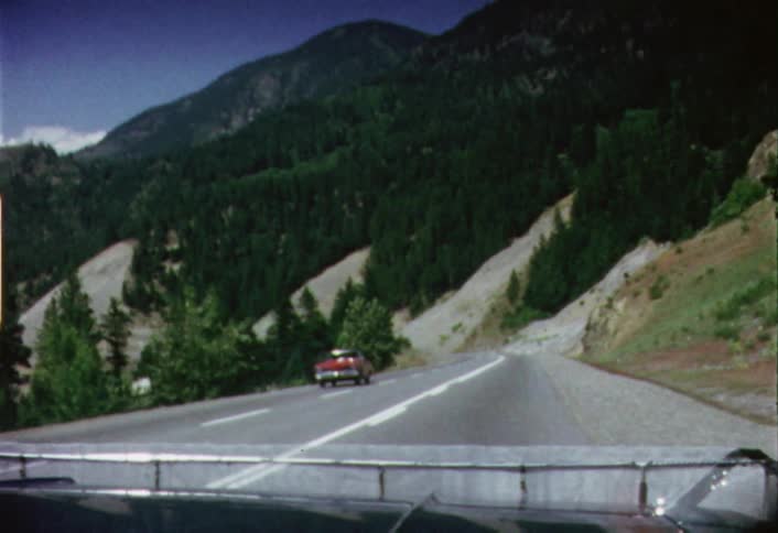 A station wagon vehicle travels down a mountain road