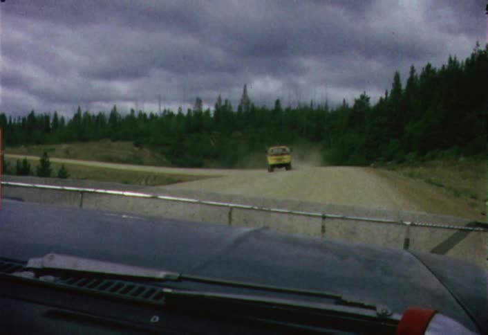A car driving down a dusty road on a cloudy day