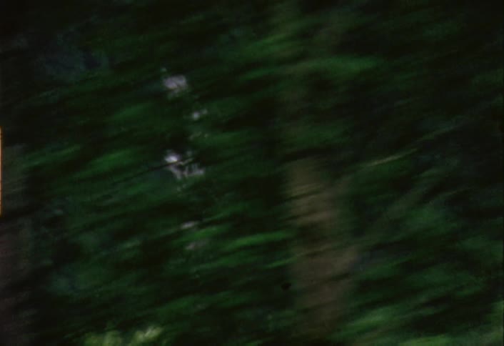 A vehicle is driving by a waterfall in a wooded area
