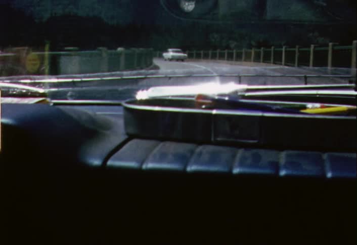 Moving view of a vehicle driving  down a two lane road as seen from just behind the dashboard