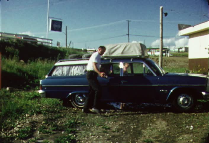 A man is wiping down his car on a sunny day