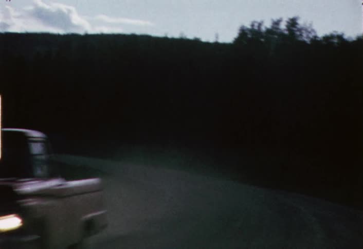 Shaky view  of a winding road with some traffic at dusk