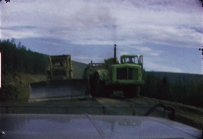 Farm and construction vehicles pass by on this dirt road