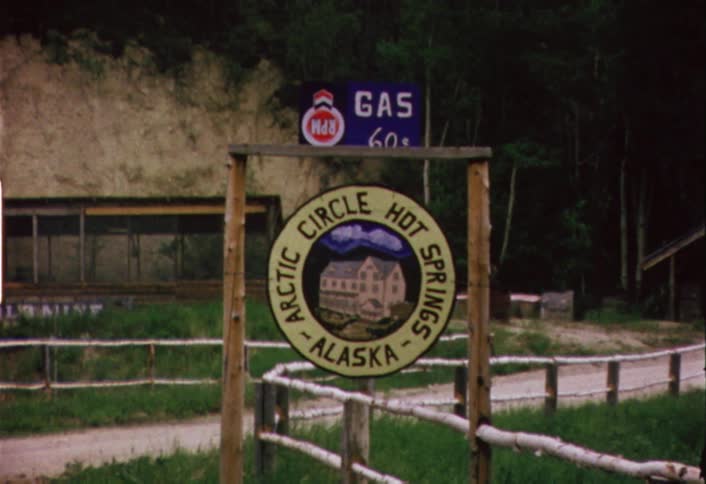 A wood sign hangs in front of a forest