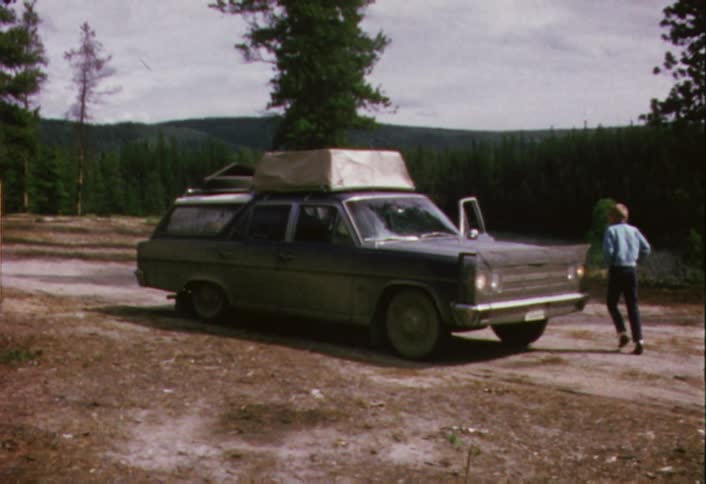 A boy closes the driver's door on a station wagon
