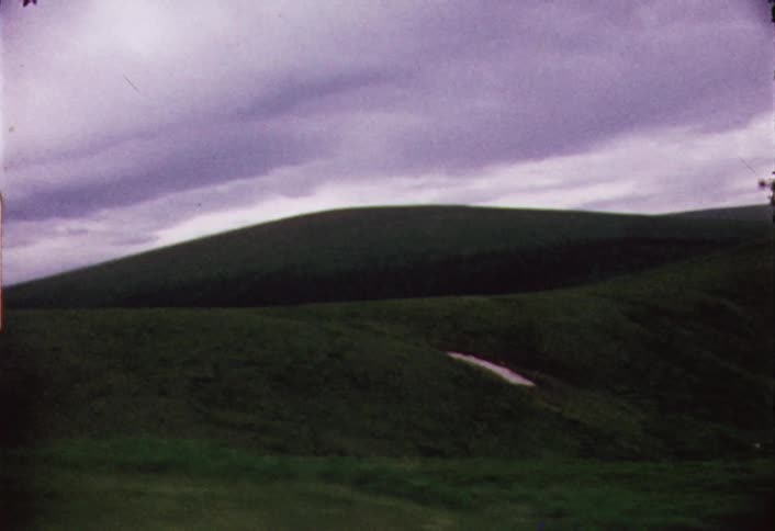 View from a vehicle driving by a hilly area