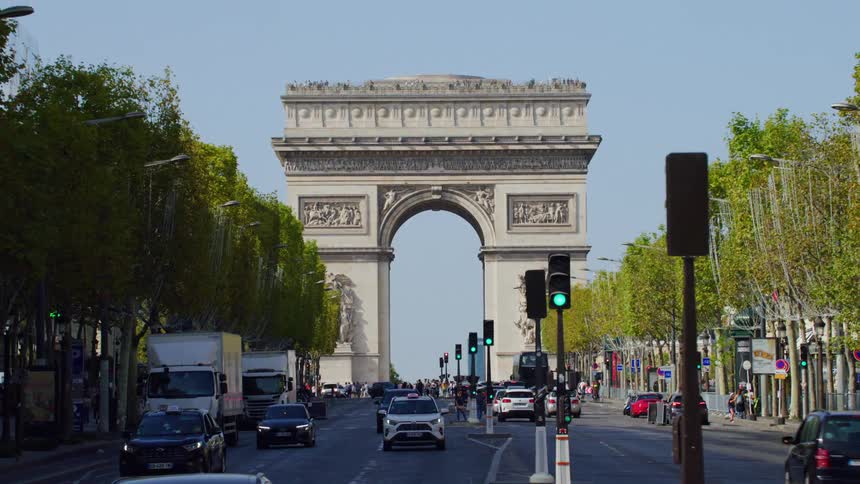 The arc de triomphe stands at the end of a bustling avenue