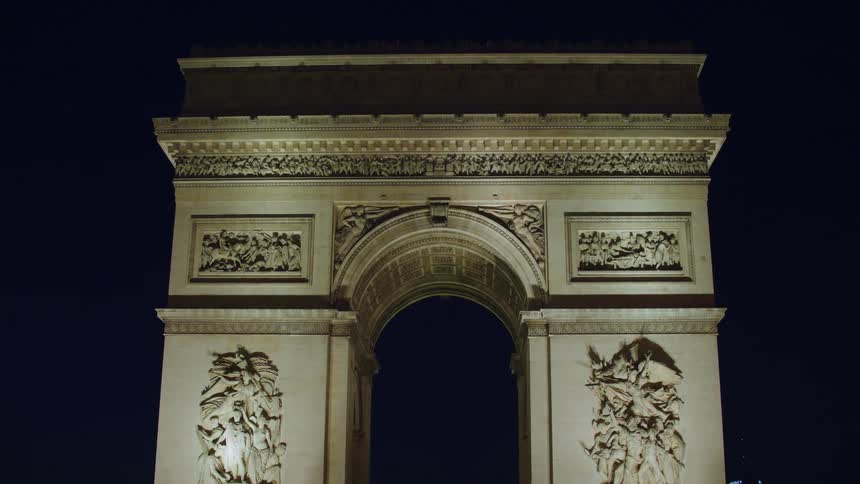 The arc de triomphe stands illuminated at night