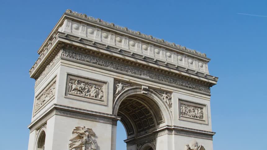 Arc de triomphe decorated by reliefs and sculptures towers over nearby trees