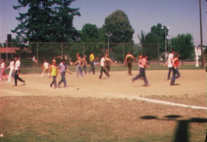 A group of people playing baseball on a local baseball field