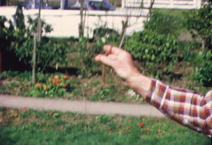 A man holds up a large worm near a chair