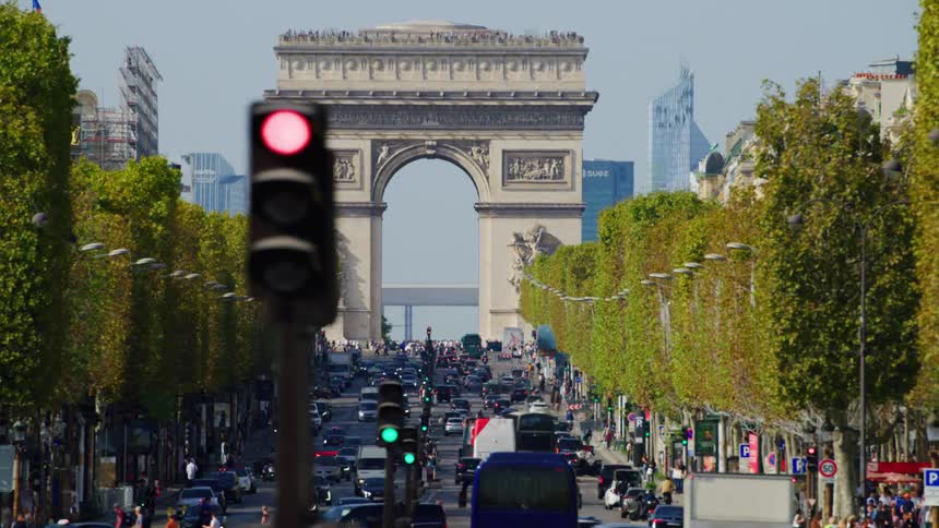 The arc de triomphe stands at the end of a bustling avenue