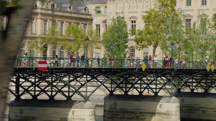 People on a parisian street and crossing a metal bridge over the river seine