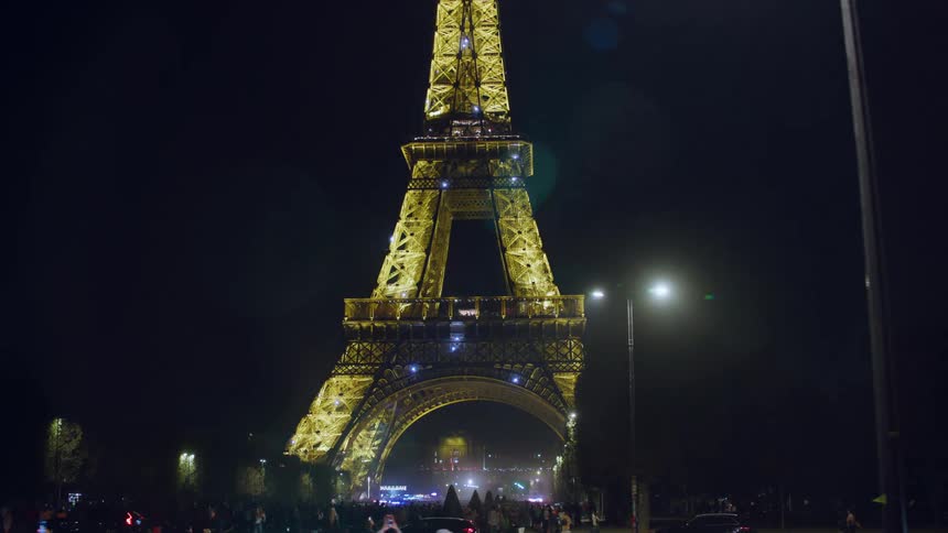 People and vehicles moving near the eiffel tower at night