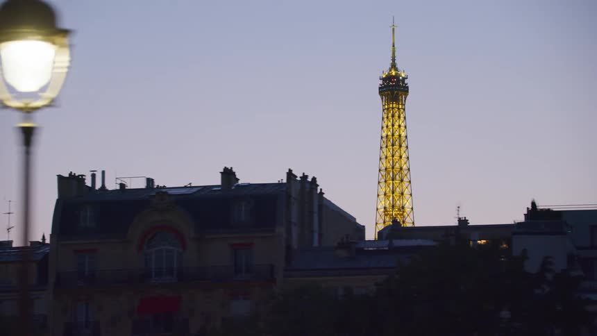 Eiffel tower towers over apartment buildings bordering highway at night