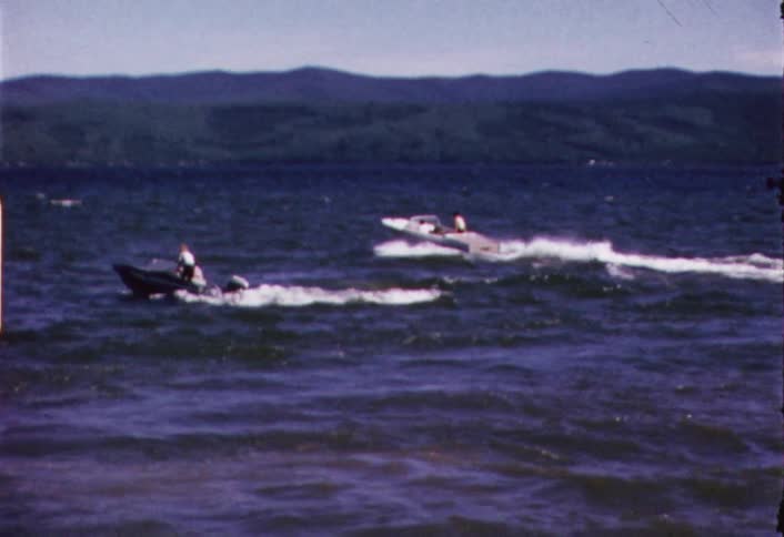 A motorboat speeds around a lake on a sunny day