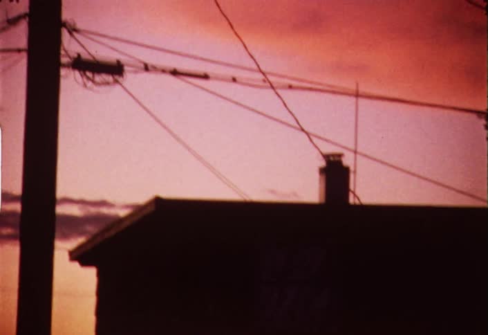 Shaky view of some power lines and houses at a colorful sunset