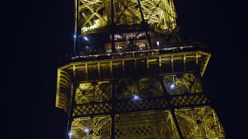 The eiffel tower at night with its lights on and some of them are blinking