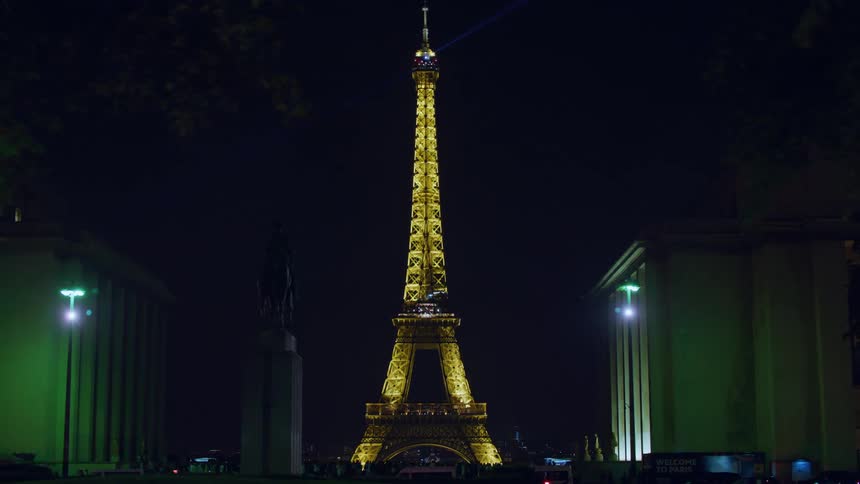 A night view of the eiffel tower lit up at night surrounded by trees and buildings