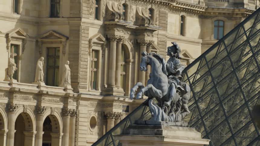 Statue of a warrior on top of a horse next to a mirrored museum pyramid