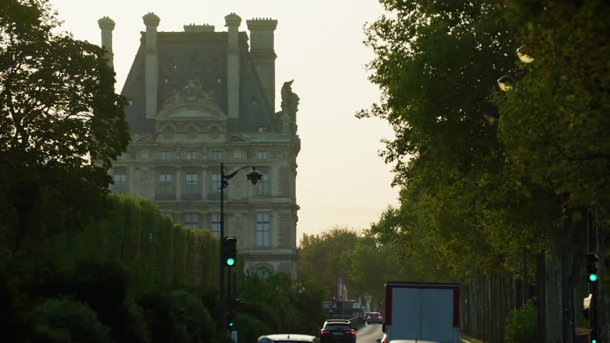 Traffic drives down street past multistory house with multiple towers
