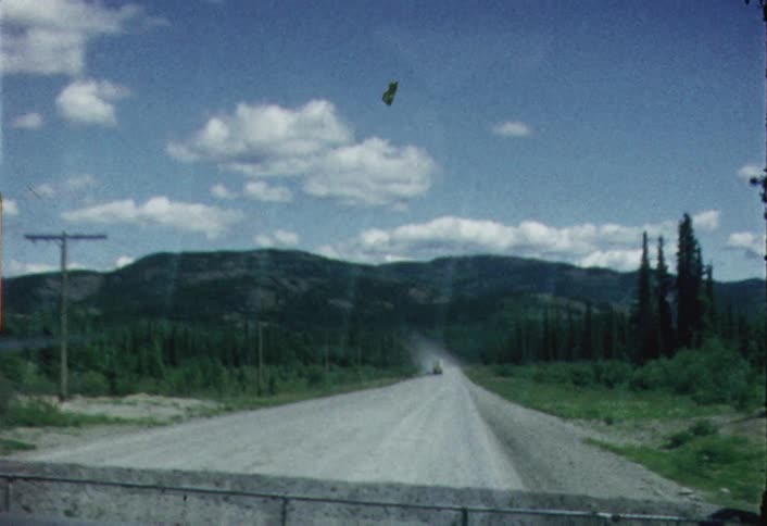 A truck is kicking up dust on a dirt road during the day