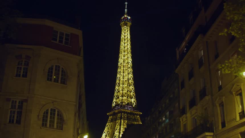 Urban buildings on the streets at night in the city of france with the eiffel tower in the background illuminated