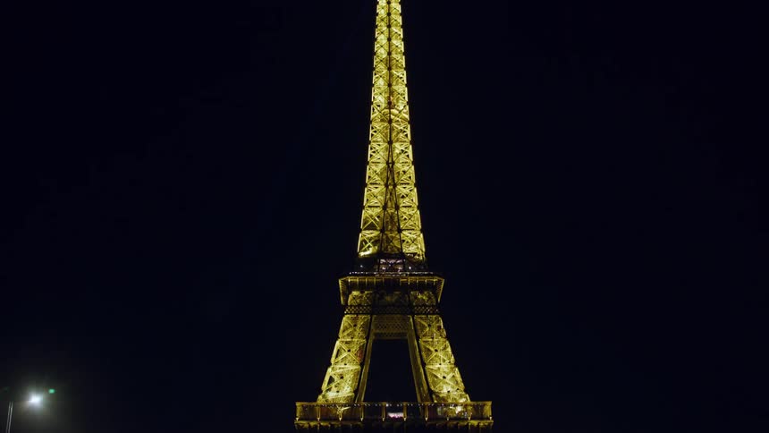 Golden light illuminating the eiffel tower contrasts with dark night sky
